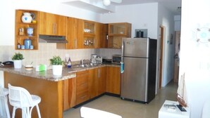 Una cocina con armarios de madera, un refrigerador de acero inoxidable y un ventilador de techo.