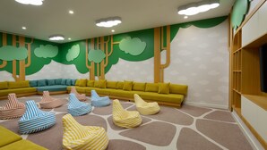 A children's play area with a green wall, a yellow sofa, and striped bean bags. - Rixos Water World Aktau (Aktau)