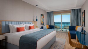 A hotel room with a large bed, a desk, and a balcony with a view of the sea. - Rixos Water World Aktau (Aktau)