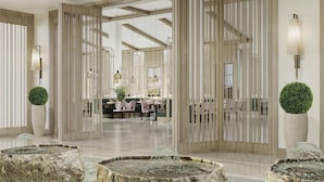 A spacious lobby with a modern design, featuring a central seating area, a reception desk, and a decorative water feature. - Rixos Water World Aktau (Aktau)