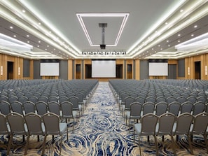 A conference room with rows of chairs, a large screen, and a patterned carpet. - Rixos Water World Aktau (Aktau)