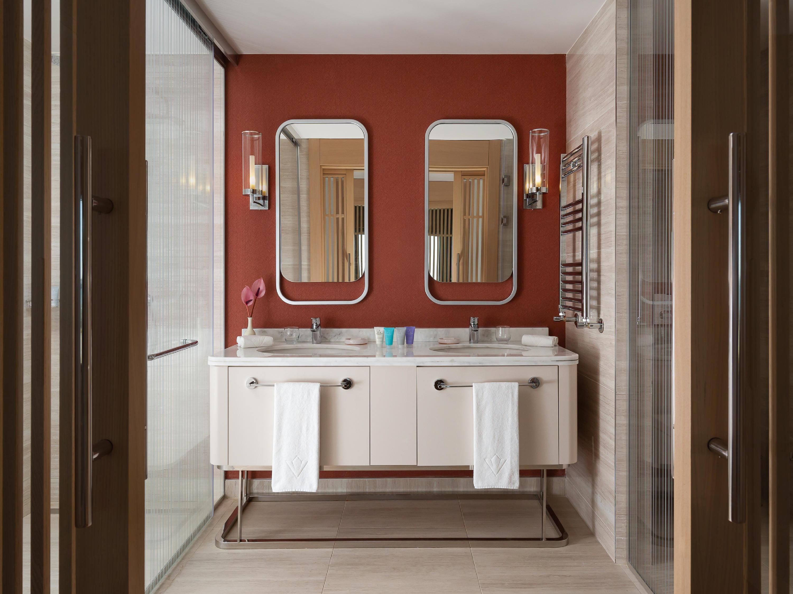 Un baño moderno con dos lavamanos, un espejo grande y una cabina de ducha de vidrio.