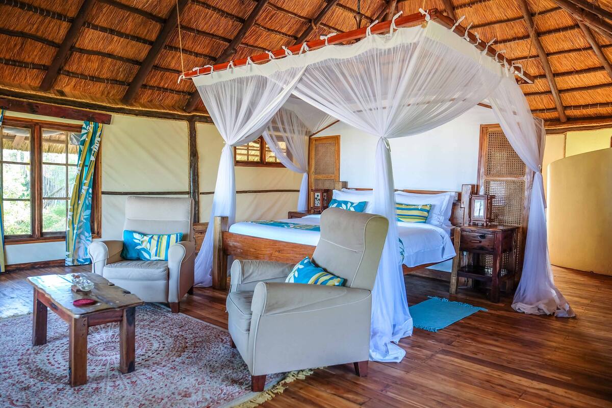 A room with a bed, a chair, a small table, and a canopy bed.