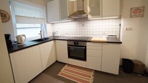 Uma cozinha moderna com armários brancos, um forno de aço inoxidável, uma pia e uma janela.