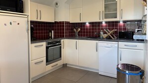 A modern kitchen with white cabinets, a microwave, oven, and dishwasher. - Cozy 2-Bedroom Apartment with Balcony & Free Parking in Villard-de-Lans (Villard-de-Lans)