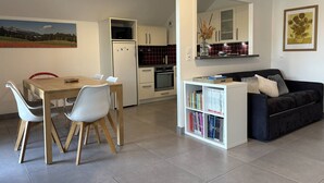 A modern living space with a dining area, kitchenette, and a cozy seating area with a bookshelf. - Cozy 2-Bedroom Apartment with Balcony & Free Parking in Villard-de-Lans (Villard-de-Lans)