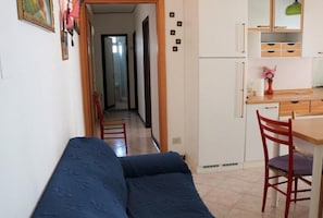 Un corridoio stretto che porta a una cucina con una panca e delle sedie.