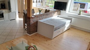 A modern living room with a glass coffee table, a sofa, a brick fireplace, and a TV. - Vacation apartment "Auf der Warf" (Wittmund)