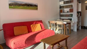 Una sala de estar con un sofá rojo, una mesa de madera y estanterías llenas de libros.