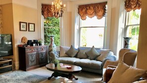Una sala de estar con sofá, mesa de centro, televisor y un jarrón decorativo.