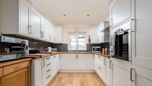 A modern kitchen with white cabinetry, a wooden countertop, and a built-in oven. - Mews Hill Fordingbridge (Fordingbridge)
