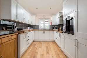 Una cocina moderna con armarios blancos, encimera de madera y horno empotrado.