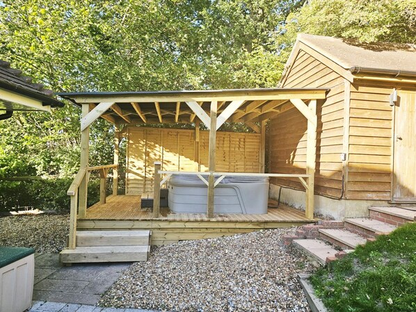 A wooden cabin with a covered patio area, a hot tub, and a small deck. - Mews Hill Fordingbridge (Fordingbridge)