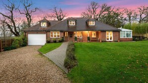 A two-story house with a garage, a front porch, and a well-maintained lawn. - Mews Hill Fordingbridge (Fordingbridge)