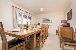 A dining area with a wooden table, chairs, a chandelier, and a framed picture on the wall. - Mews Hill Fordingbridge (Fordingbridge)