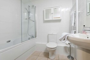 Une salle de bain avec une douche à parois de verre, des toilettes, un lavabo avec un porte-serviettes et un miroir.