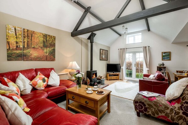 A spacious living room with a high ceiling, a fireplace, a television, and a dining area.