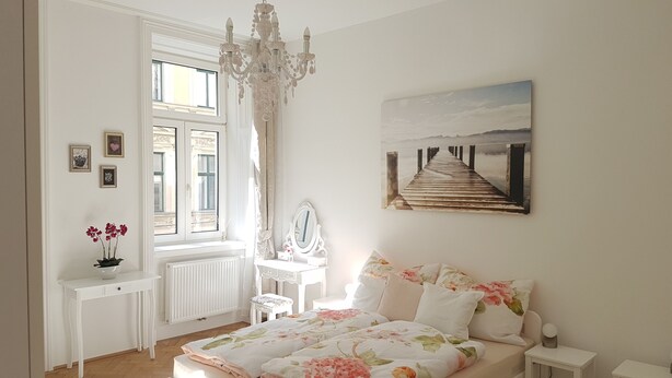 Une chambre à coucher avec un grand lit, une commode, une coiffeuse et une fenêtre avec des rideaux.