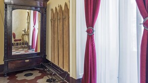 Una habitación con un espejo grande, un armario de madera y una ventana con cortinas rojas.