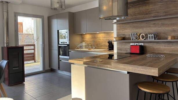 Una cocina moderna con una isla central, electrodomésticos de acero inoxidable y un muro decorativo de madera.