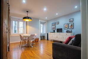 A dining area with a table and chairs, a sofa, a TV, and a cabinet. - Sé Apartment: A charming nest by the Cathedral (Lisboa)
