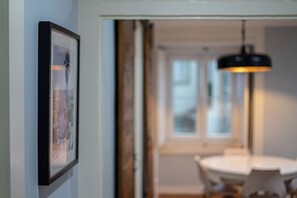 A framed picture on a wall, a round table with chairs, and a hanging light fixture. - Sé Apartment: A charming nest by the Cathedral (Lisboa)