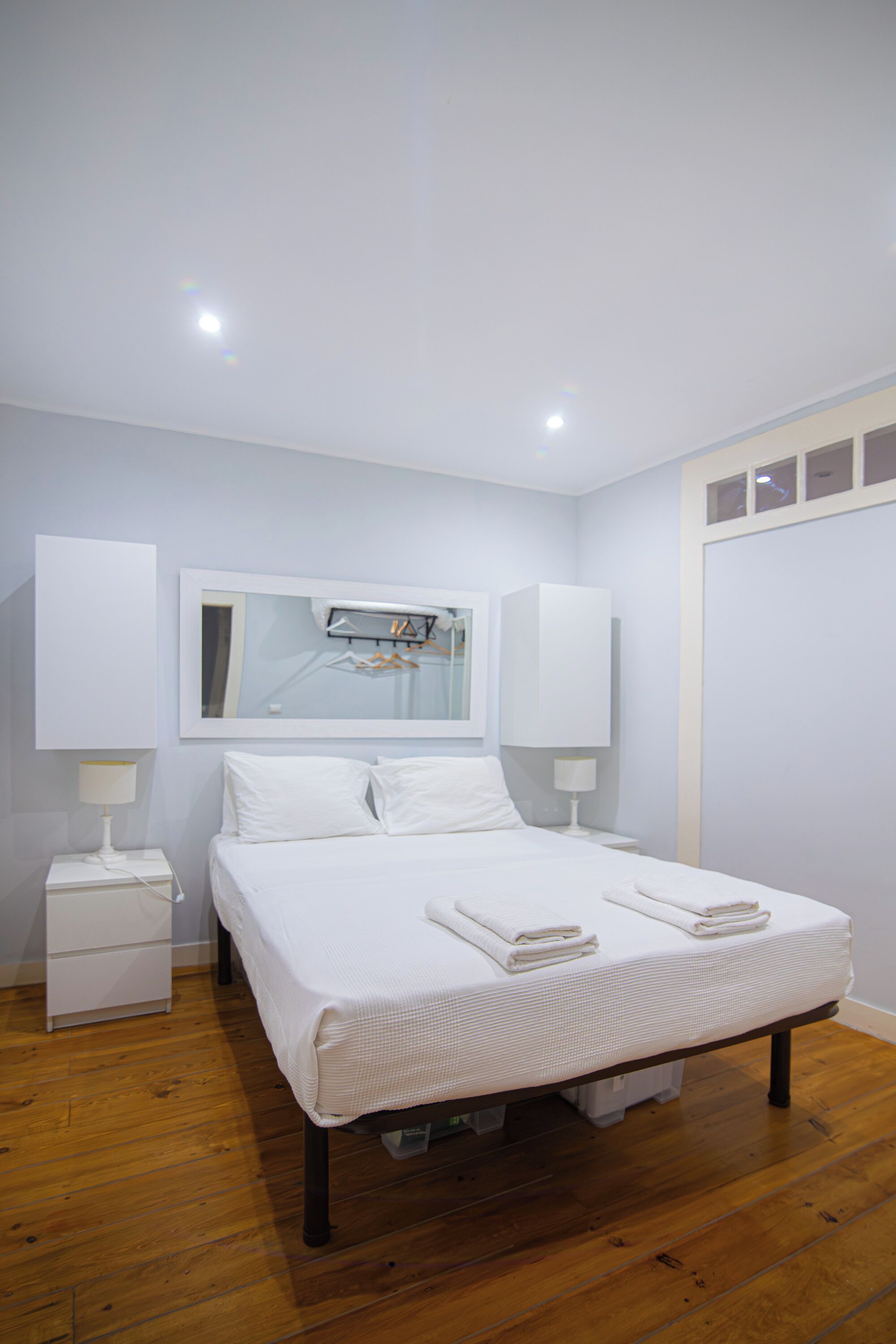 Un dormitorio con una cama, dos mesitas de noche, un espejo y un armario.