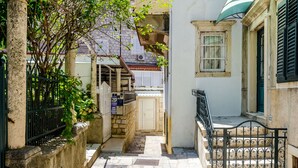 A narrow alleyway with a stone wall, a metal gate, and a small bench. - Rooms City Central Old Town (Dubrovnik)