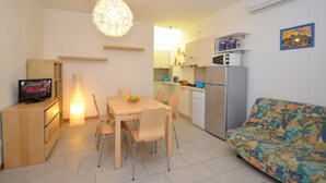 A compact living space with a dining area, kitchenette, and a sofa.