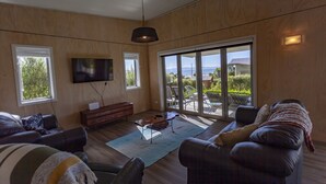 Una sala moderna con televisor grande, paredes de madera y vistas al exterior.