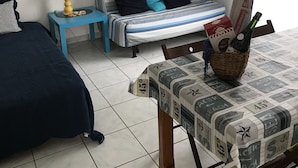 Quarto com cama, mesa de cabeceira com abajur, sofá e janela com cortinas.
