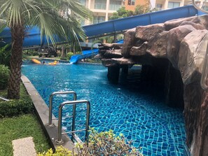 A swimming pool with a rock formation and a slide. - Laguna Beach Resort 2 - Modern Studio Condo (Pattaya)