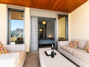 A balcony with wicker furniture, a bottle of wine, and a view of the cityscape. - Big Terrace Apartment Cullera (Cullera)
