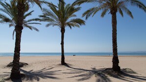 Ein Strand mit drei Palmen und freiem Blick auf den Ozean.