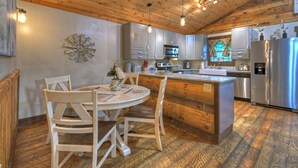 Une cuisine avec un plafond et des placards en bois, une table à manger avec des chaises et des appareils électroménagers modernes.