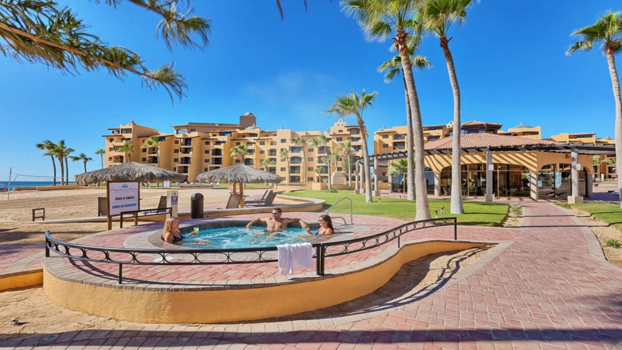 Ein Resort mit Swimmingpool, Palmen und Strand.