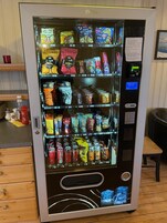 Máquina expendedora llena de aperitivos, bebidas y cubitos de hielo.