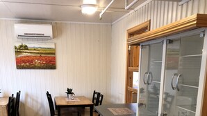 Et træbord med stole, en lille potteplante og et billede på væggen.