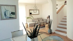 A living room with a sofa, a dining table, and a staircase. - La BouganVilla Charme & Relax with sea view (finale ligure)