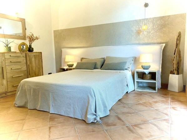 A bedroom with a bed, two bedside tables, a nightstand, a dresser, and a mirror.