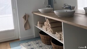 A modern bathroom with two vessel sinks, a large mirror, and a towel rack.