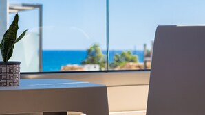 Ein modernes Zimmer mit Meerblick, einer Topfpflanze und einem schlichten Tisch.