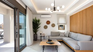 Ein modernes Wohnzimmer mit einem grauen Sofa, einem Holztisch und einer Glastür, die zu einem Außenbereich führt.