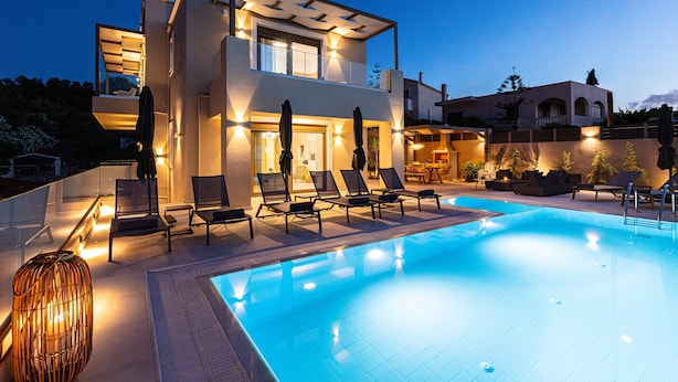 Ein modernes, zweistöckiges Haus mit Swimmingpool, Außenbereich mit Sitzgelegenheiten und einer gut beleuchteten Terrasse.