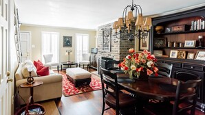 A living room with a fireplace, a dining area with a chandelier, and a bookshelf.