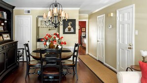 A dining area with a round table, black chairs, a chandelier, and a vase of red and white flowers.