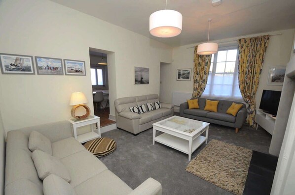 A living room with a sofa, a coffee table, a TV, and a lamp. - Quay Corner Christchurch Dorset (Christchurch)