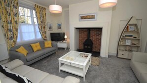 A living room with a sofa, coffee table, fireplace, television, and decorative items. - Quay Corner Christchurch Dorset (Christchurch)