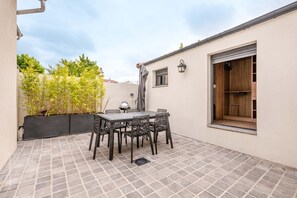 Relax in a compact patio area with a table, chairs, and grill, perfect for casual gatherings.