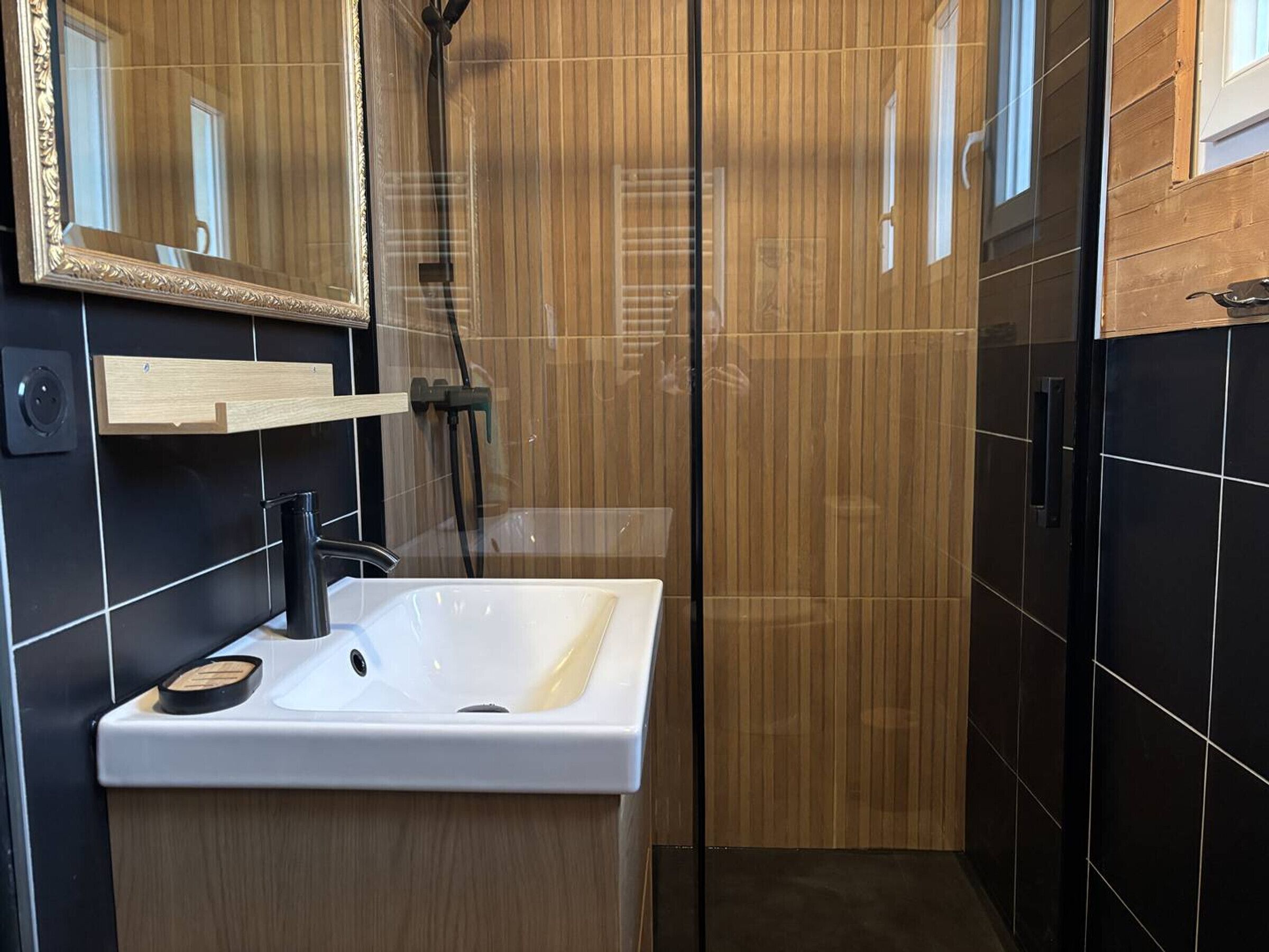 Une salle de bain moderne avec un lavabo blanc, un miroir et une cabine de douche.